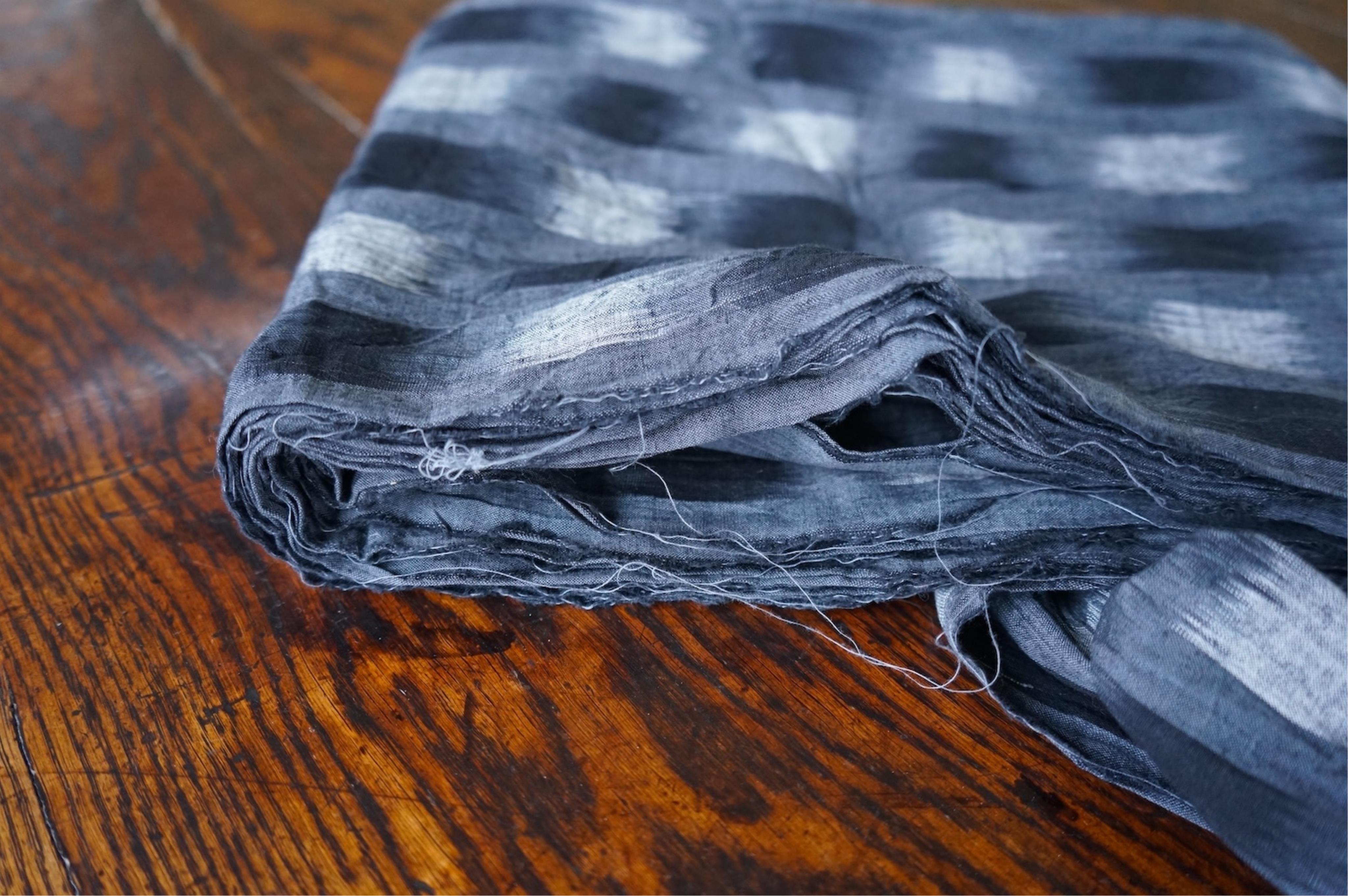 A long narrow length of grey Ikat woven fabric, a roll of Indian mirrored edging, a geometric batik printed length and a woven paisley ‘style’ tasselled stole. (4). Batik 392cm long x 108cm wide., Condition - good, all a